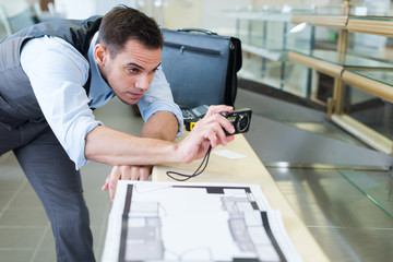 Obraz premium portrait of serious concentrated architect taking a photo of plans