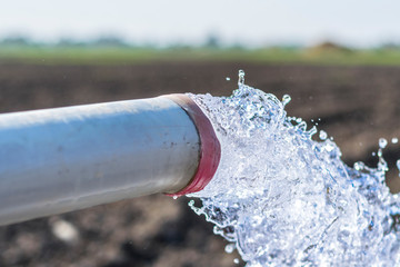 high pressure crystal bluish sweet water flushing out of an agriculture industrial tube waell in fields  