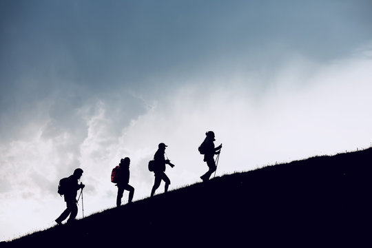 Four hikers silhouettes goes uphill