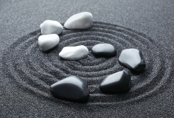 Fototapeta na wymiar Stones on black sand with beautiful pattern. Zen and harmony