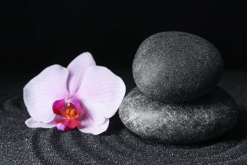 Obraz na płótnie Canvas Spa stones and orchid flower on black sand with beautiful pattern. Zen concept