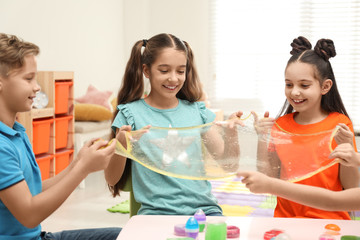 Happy children playing with slime at table indoors