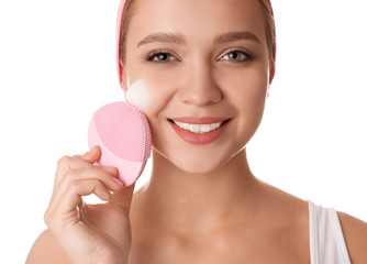 Young woman washing face with brush and cleansing foam on white background. Cosmetic products