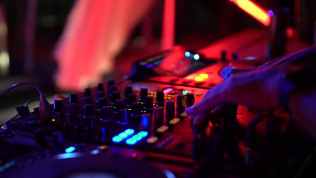DJ operating mixing desk at party, close up