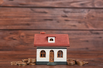 House model and coins on wooden background