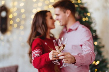 Close up photo of two people holding glasses of shampagne on xmas