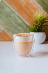 glass of latte coffee on light table with almond nuts