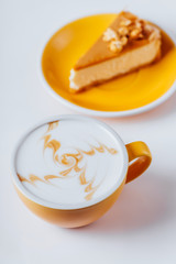 Cup of hot cappuccino coffee with cake on white table with copy space
