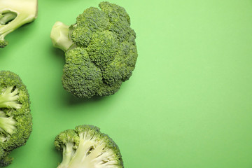 Fresh broccoli on green background, flat lay. Space for text