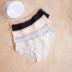 Women's panties and lingerie bag for laundry on beige background. Female underwear texture.