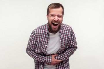 Obraz premium Portrait of extremely excited happy bearded man in casual plaid shirt holding his belly and laughing out loud, chuckling giggling at amusing joke. indoor studio shot isolated on white background