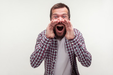 Attention! Portrait of enraged mad bearded man in casual plaid shirt yelling loudly holding arms...