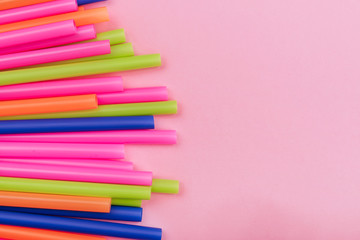colored tubules for juice and cocktails on pink background. Colorful drink straws. straw, plastic free, reusable plastic drinking background, plastic free. Plastic pollution concept.