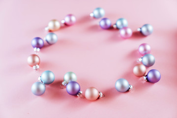 From above shot of bright glittering baubles composed in row on pink background.