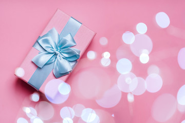 Gift box with Blue ribbon on Pink background for copy space. Christmas minimal concept idea.