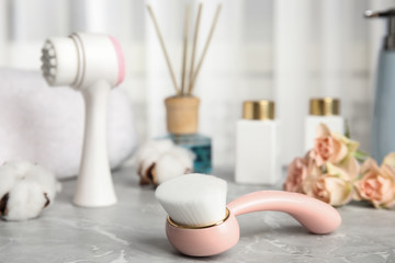Modern face cleansing brush on light grey marble table. Cosmetic accessory