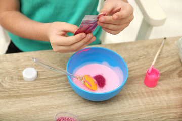 Little girl making homemade slime toy at table, closeup