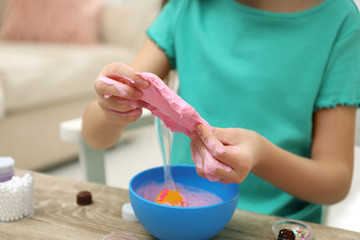 Obraz na płótnie Canvas Little girl making DIY slime toy at table indoors, closeup