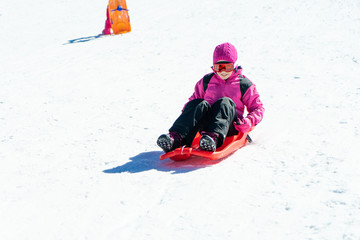 Fototapeta na wymiar Little girl sledding at Sierra Nevada ski resort.