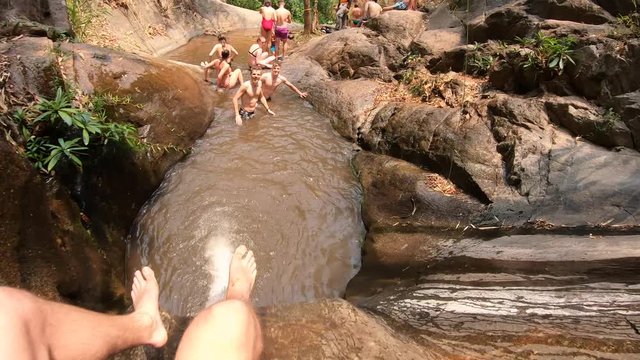 POV of Male Sliding down a Rock in Thailand Jungle landing in a Pool of Water