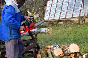 Sawing wood with chainsaw with safety glasses and helmet
