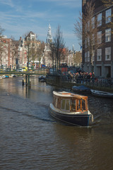 A canal boat making its way down Amsterdam canal in Winter