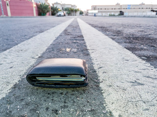 A Black Lost Wallet Made by Leather Fallen on ground near a Shopping Mall at Night