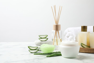 Different cosmetic products and aloe on white marble table. Space for text