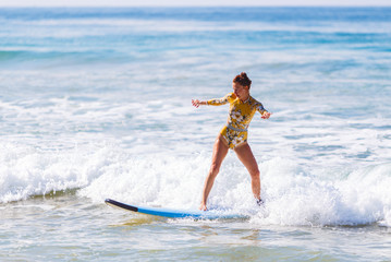 young girl rolls on surfboard, starts to learn, not a professional, against the waves of the ocean, Sri Lanka.