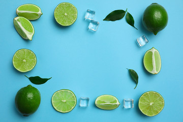 Flat lay composition with fresh juicy limes and ice cubes on light blue background. Space for text