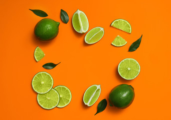 Flat lay composition with fresh juicy limes on orange background. Space for text