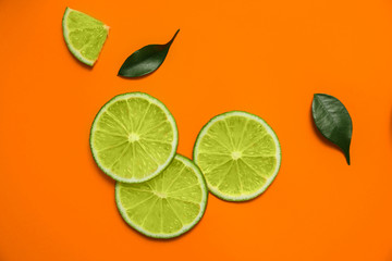 Flat lay composition with slices of fresh juicy lime on orange background