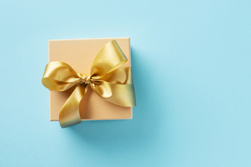 Gift box with golden ribbon on bright background