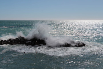 Horizon line over sea and a wave is crashing stones.