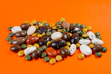 Pebble-dragee with apricots, chocolate, mandarin and marzipan. Tasty, bright, shot on an orange background.