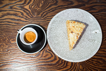 A slice of Esterhazy cake on a gray plate close-up on the table and a cup of espresso