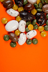 Pebble-dragee with apricots, chocolate, mandarin and marzipan. Tasty, bright, shot on an orange background.