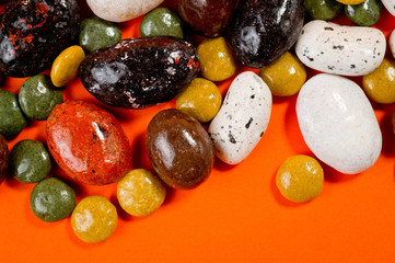 Pebble-dragee with apricots, chocolate, mandarin and marzipan. Tasty, bright, shot on an orange background.
