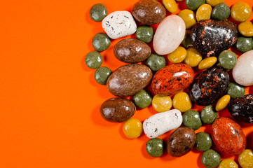 Pebble-dragee with apricots, chocolate, mandarin and marzipan. Tasty, bright, shot on an orange background.