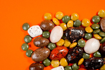 Pebble-dragee with apricots, chocolate, mandarin and marzipan. Tasty, bright, shot on an orange background.