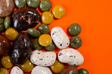 Pebble-dragee with apricots, chocolate, mandarin and marzipan. Tasty, bright, shot on an orange background.