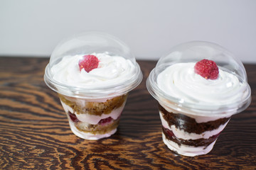 Delicious yogurt desserts with raspberries on a large wooden table
