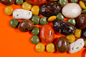 Pebble-dragee with apricots, chocolate, mandarin and marzipan. Tasty, bright, shot on an orange background.