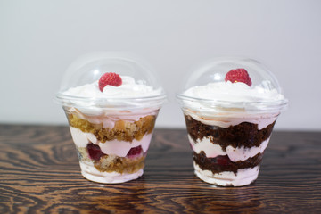 Delicious yogurt desserts with raspberries on a large wooden table