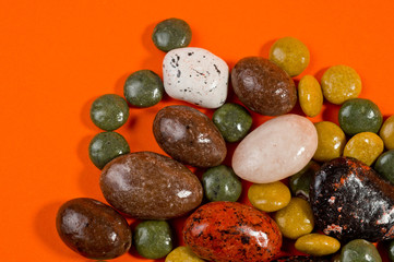 Pebble-dragee with apricots, chocolate, mandarin and marzipan. Tasty, bright, shot on an orange background.