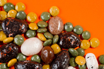 Pebble-dragee with apricots, chocolate, mandarin and marzipan. Tasty, bright, shot on an orange background.
