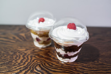 Delicious yogurt desserts with raspberries on a large wooden table