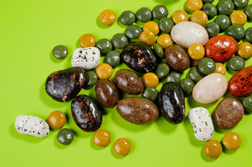 Pebble-dragee with apricots, chocolate, mandarin and marzipan. Tasty, bright, shot on a green background