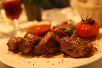 pork shish kebab with salad, sauce and tomatoes on the grill