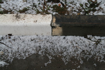 the first snow near the curb on the road